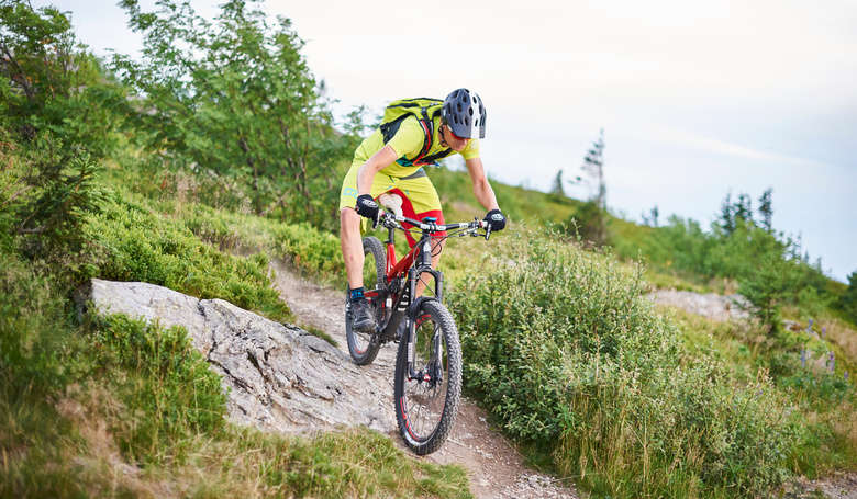 Mountainbiker fährt gerade über einen schmalen Weg nach unten