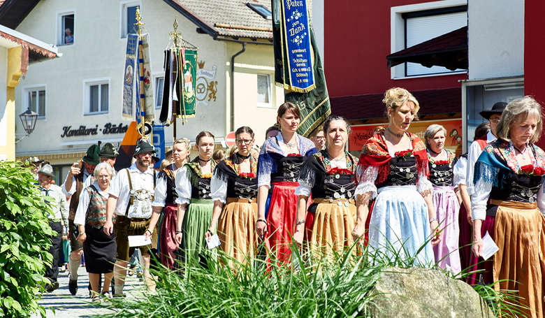 Festzug durchs Dorf mit Frauen und Männern in Tracht