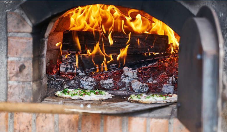 Offener Ofen vor dem zwei Flammkuchen liegen